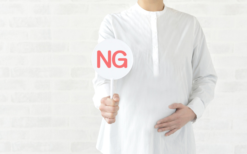 NGの文字が描かれたプレートを持つ妊婦